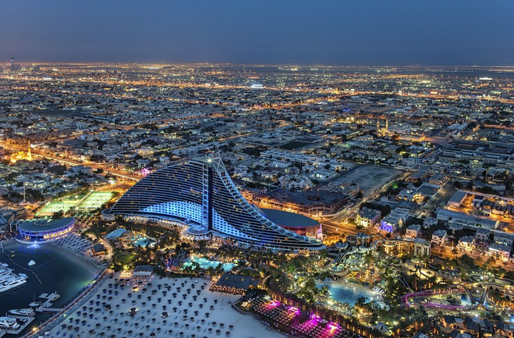 Aerial view of the cityscape of Dubai, United Arab Emirates at dusk, with the Jumeirah Beach Hotel