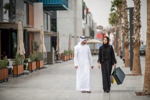 Dubai Tipps und Infos Middle eastern shopping couple wearing traditional clothing carrying shopping bags, Dubai, United